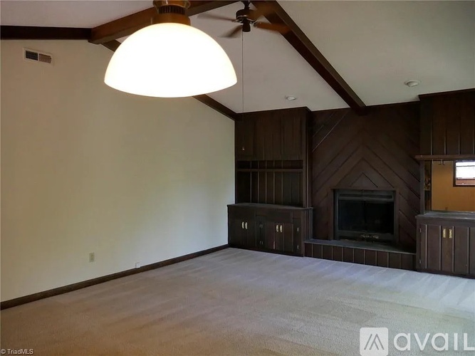 A living room with a fireplace and wooden cabinets.