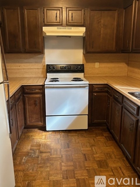 A kitchen with a white stove top oven and wooden cabinets.