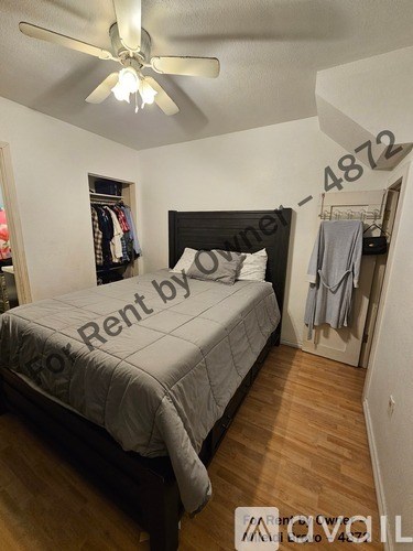 A bedroom with a bed, a ceiling fan, and a sign that says "Rent by".