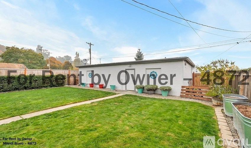 A white building with a green lawn in front and a sign that says "For Rent by Owner - Milford Bravo - 4872".