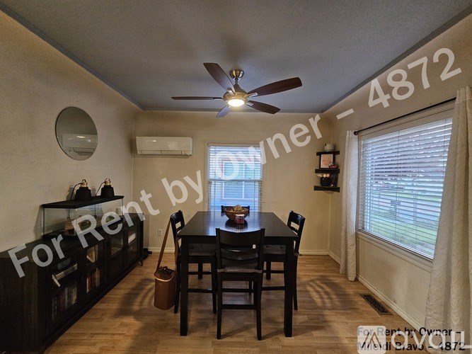 A dining room with a table set for two and a ceiling fan.