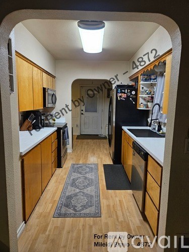 A kitchen with wooden cabinets and a black fridge.