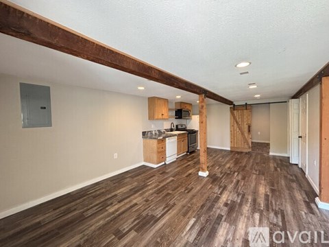 A room with wooden flooring and a kitchen area with wooden cabinets.