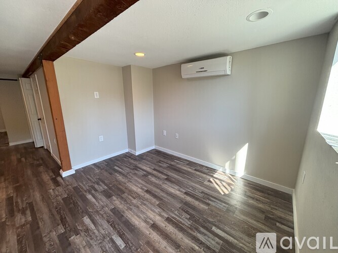 A room with a wooden floor and a wall-mounted air conditioner unit.