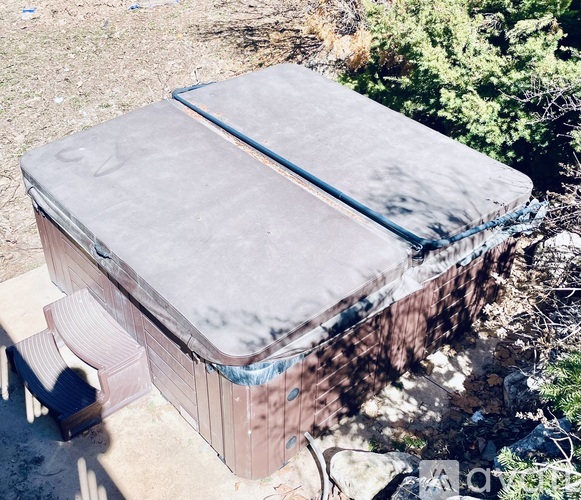 A hot tub is covered with a grey tarp.