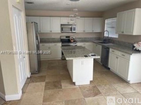A kitchen with white cabinets and a tiled floor.