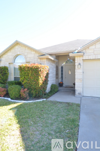 A house with a white garage door and a green hedge in front.