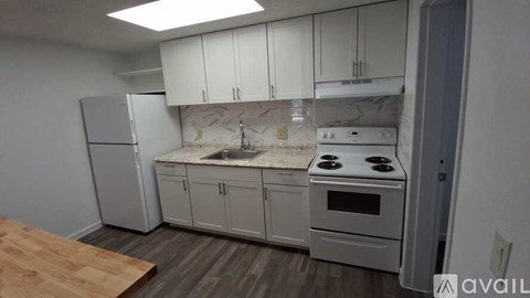 A kitchen with white cabinets and a wooden floor.