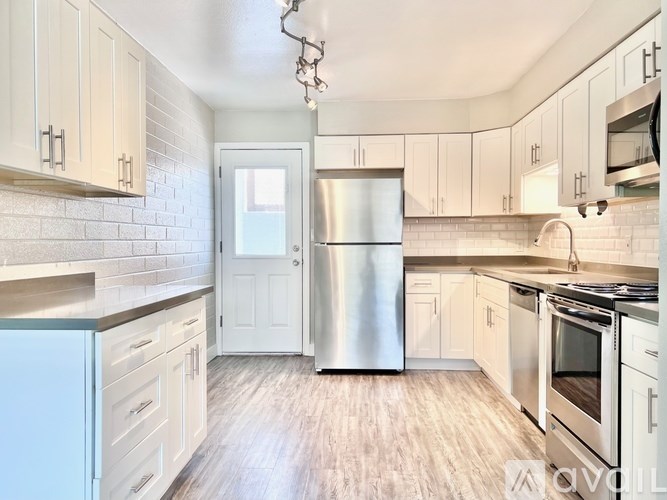 A kitchen with white cabinets and a stainless steel refrigerator.