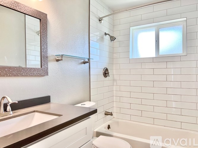 A bathroom with a white tiled wall and a window.