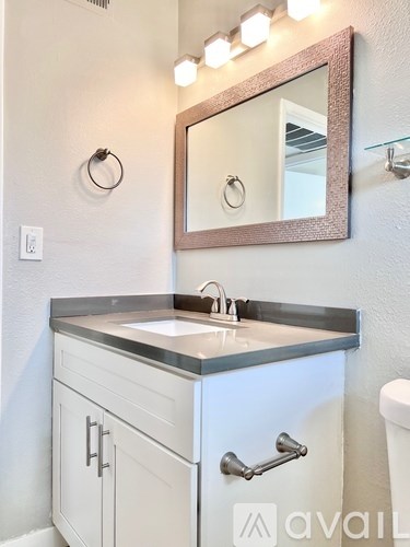 A bathroom with a sink, mirror, and lights.