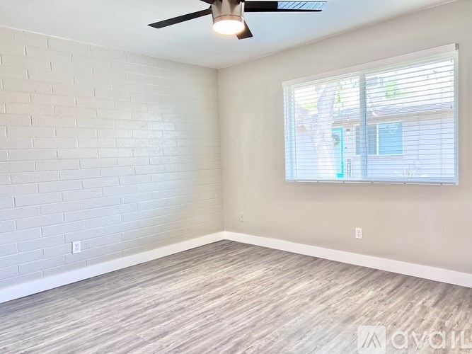 A room with a ceiling fan and a window with blinds.