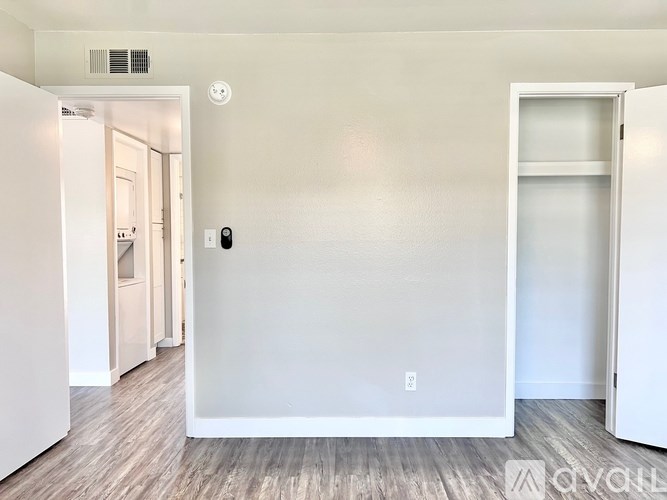 A room with a white door and a white wall with a light switch.