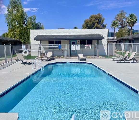 A swimming pool with lounge chairs and a building in the background.