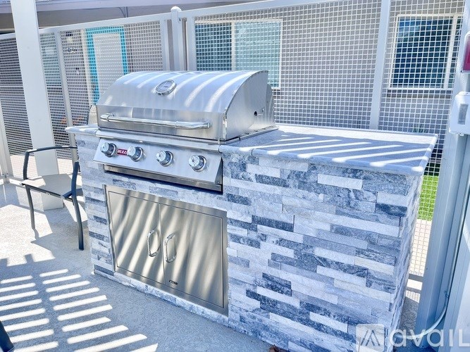 A silver grill with a stone backsplash is on a patio.