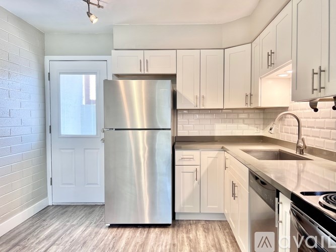 A kitchen with a stainless steel refrigerator and white cabinets.