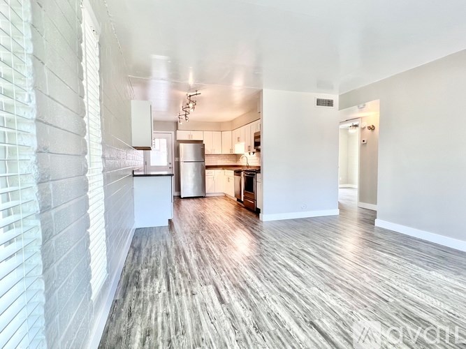 A spacious room with wooden flooring and white walls.