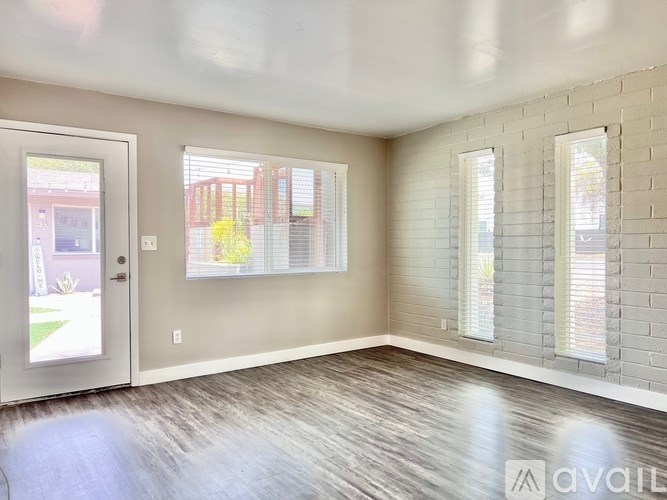 A room with a door, two windows, and a brick wall.