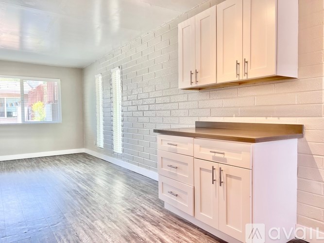 A kitchen with white cabinets and a brick wall.