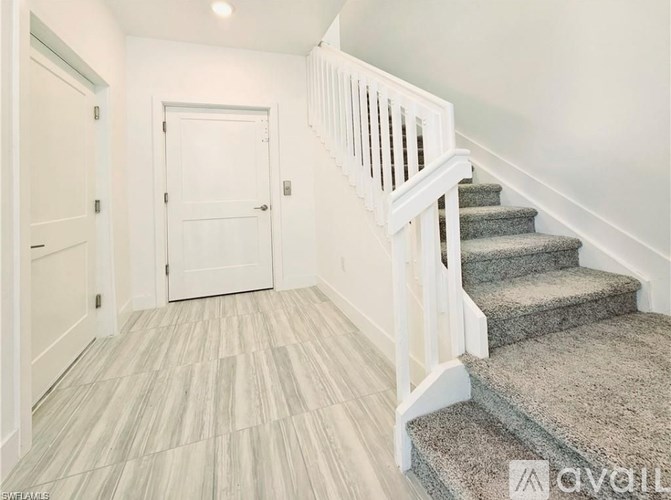 A hallway with a staircase and a white door.
