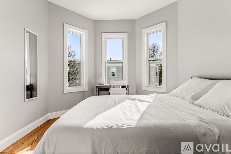 A bedroom with a large bed and three windows.
