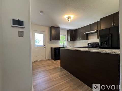 A kitchen with dark brown cabinets and a black stove top oven.