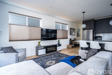 A modern living room with a grey sofa set and a television mounted on the wall.