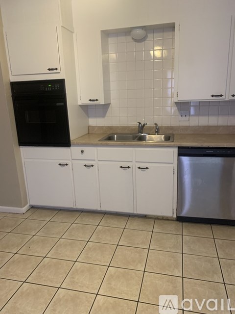A kitchen with white cabinets and a black oven.
