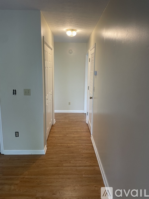 A long hallway with wood floors and white walls.