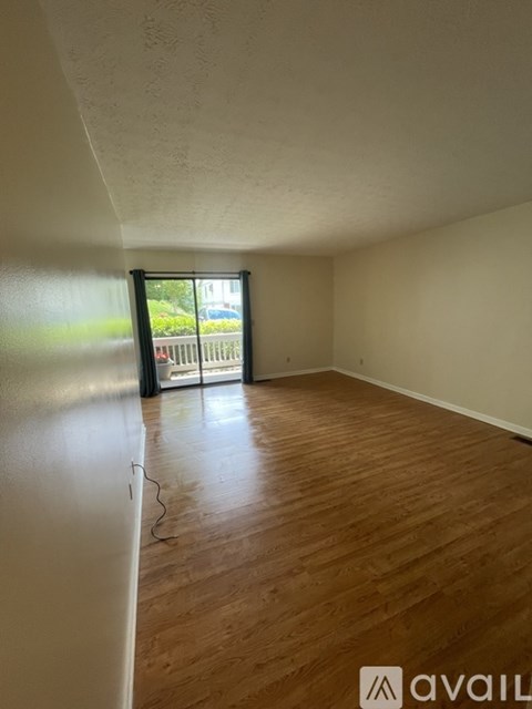 A room with wooden floors and a window overlooking a fence.