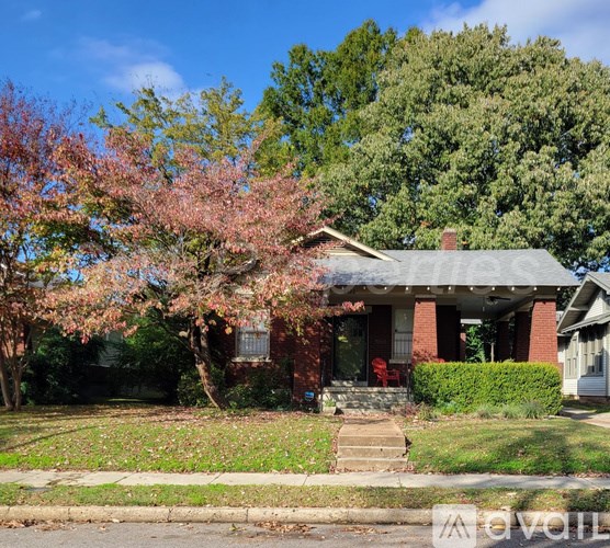 A house with a red door and a tree with pink flowers in front.