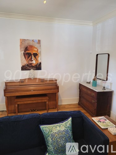 A living room with a couch, a piano, and a painting on the wall.