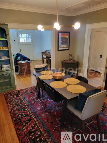 A dining room with a rug and a table with chairs.