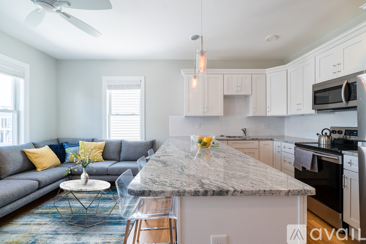 A modern kitchen with a grey granite countertop and white cabinets.