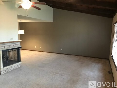 A spacious room with a fireplace and a ceiling fan.