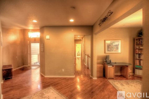 A spacious living room with hardwood floors and a rug in the center.