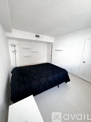 A bedroom with a bed and a white wall.