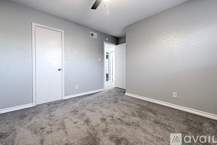 A room with a carpeted floor and a ceiling fan.