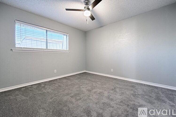 A room with a ceiling fan and a window with blinds.