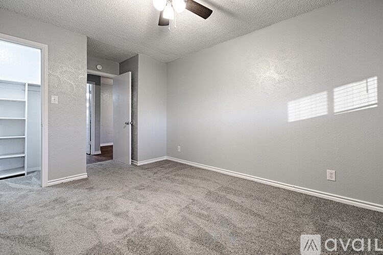 A room with a carpeted floor and a ceiling fan.