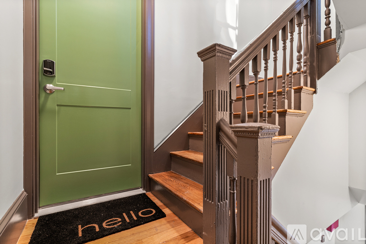 A green door with a white handle and a black doormat with the word "hello" written on it.