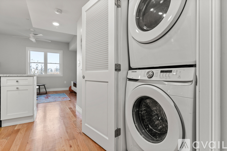 A white washing machine is in a white cabinet in a laundry room.