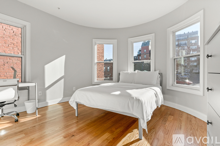 A bedroom with a large bed and a desk with a chair.