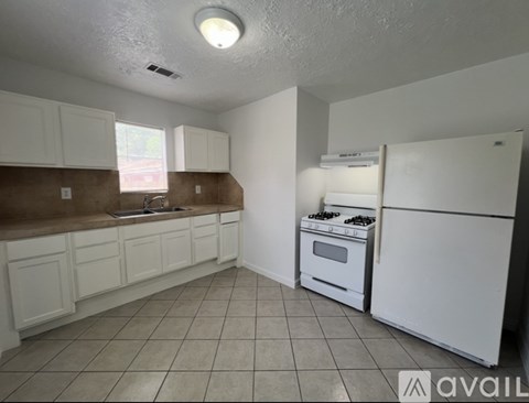 A kitchen with white cabinets and a white refrigerator.