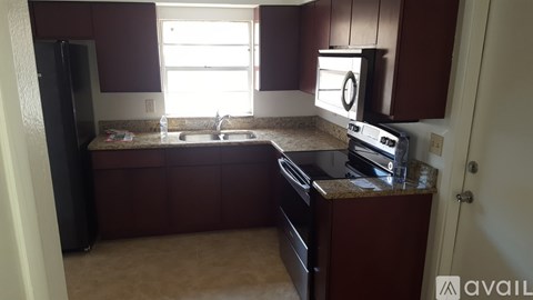 A kitchen with brown cabinets and a black refrigerator.
