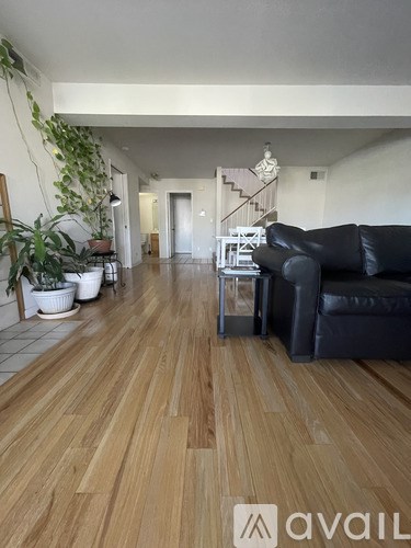 A living room with a black couch and wooden floors.