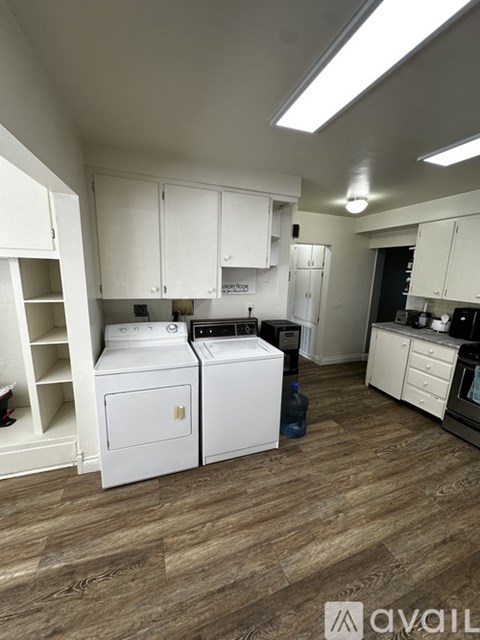 A kitchen with white cabinets and a wooden floor.