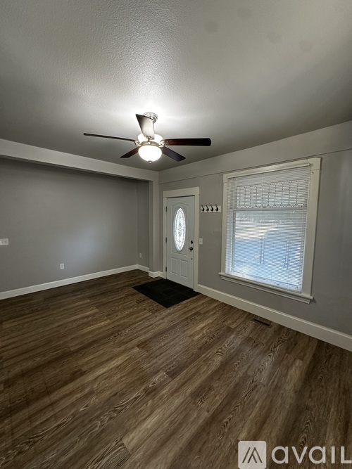 A room with wooden flooring and two windows.