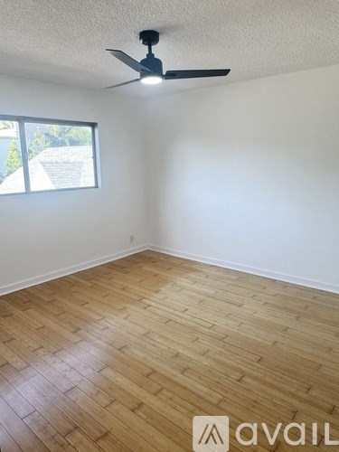 A room with a ceiling fan and wooden flooring.