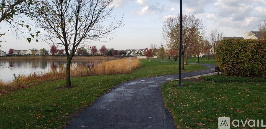 A pathway in a park with a body of water and trees.